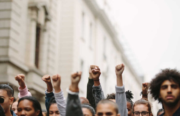 Arms,Raised,In,Protest.,Group,Of,Protestors,Fists,Raised,Up