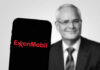 ExxonMobil logo on phone, blurred man in background.