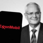 ExxonMobil logo on phone, blurred man in background.