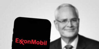 ExxonMobil logo on phone, blurred man in background.