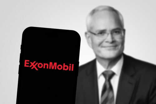 ExxonMobil logo on phone, blurred man in background.