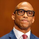 Man in a suit with glasses displaying a serious expression