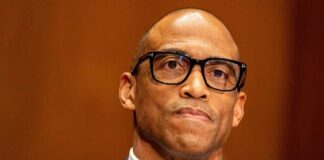 Man in a suit with glasses displaying a serious expression