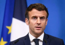 Man speaking at podium in front of flags