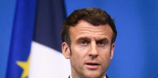 Man speaking at podium in front of flags