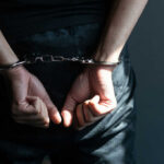 Person with hands cuffed behind back in handcuffs