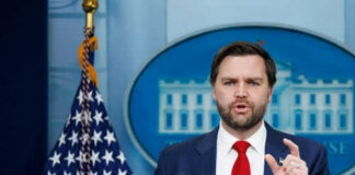 Man speaking at podium with US flag behind