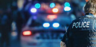Police officer standing near patrol car with lights