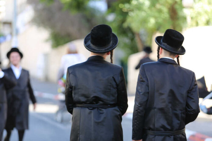 Two men in traditional black attire and hats walking down a street