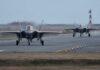 Two F-35 fighter jets on an airfield preparing for takeoff