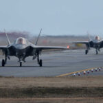 Two F-35 fighter jets on an airfield preparing for takeoff