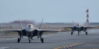 Two F-35 fighter jets on an airfield preparing for takeoff