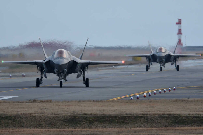 Two F-35 fighter jets on an airfield preparing for takeoff