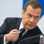 A man in a suit gesturing during a discussion