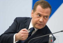 A man in a suit gesturing during a discussion