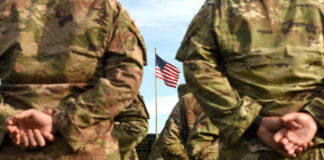 Soldiers standing in formation with an American flag in the background