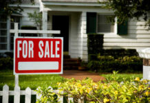 A 'For Sale' sign in front of a house