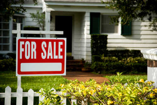 A 'For Sale' sign in front of a house