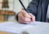 A student's hand holding a pencil while filling out a test paper
