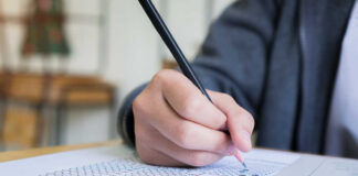 A student's hand holding a pencil while filling out a test paper