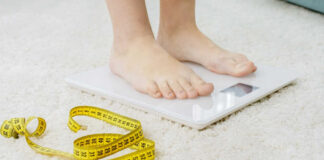 Person standing on a digital scale with a measuring tape nearby