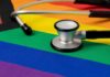 A stethoscope resting on a rainbow flag background