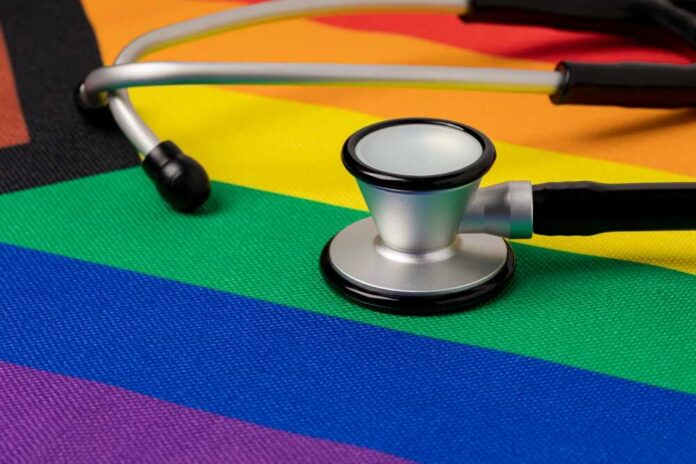 A stethoscope resting on a rainbow flag background