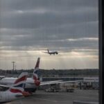 An airplane landing at an airport with other planes parked nearby