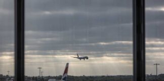 An airplane landing at an airport with other planes parked nearby