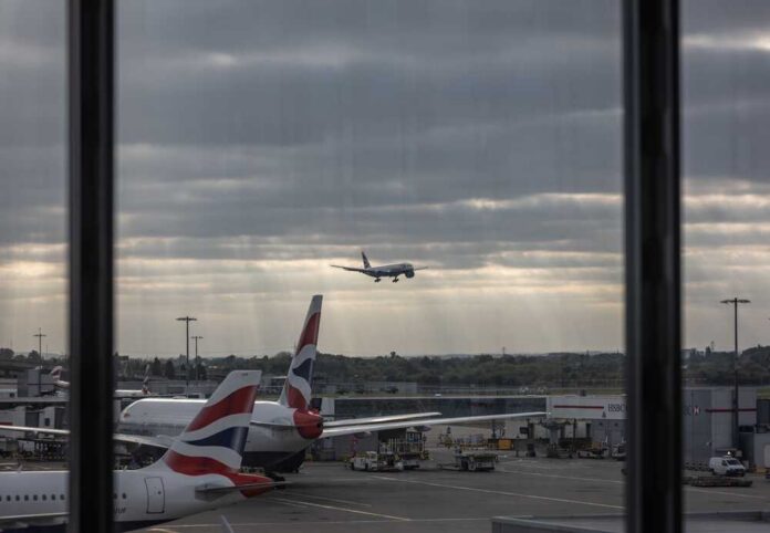 An airplane landing at an airport with other planes parked nearby
