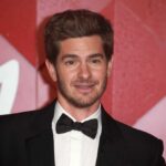 Andrew Garfield smiling at a red carpet event in formal attire