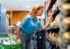 Woman shopping in a supermarket aisle, examining products on the shelf