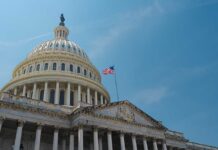 The U.S. Capitol building with an American flag flying against a blue sky