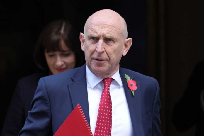 A man in a suit with a red tie and poppy flower, walking outdoors