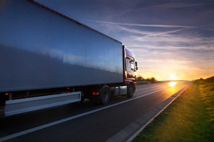 A truck driving on a highway during sunset