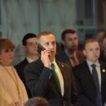 Man in a suit making a phone call at a crowded event