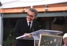 A man in a black suit delivering a speech at a Hollywood event