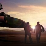 Two pilots walking towards a fighter jet at sunset