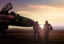 Two pilots walking towards a fighter jet at sunset