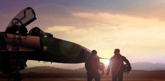 Two pilots walking towards a fighter jet at sunset