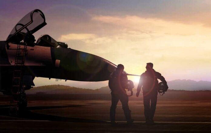 Two pilots walking towards a fighter jet at sunset