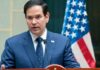 Rubio’s SHOCKING NATO Threat—Reexamine Alliance NOW A man in a blue suit speaking into a microphone with an American flag in the background