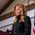 Woman speaking at podium with American flag background