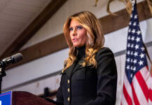 Woman speaking at podium with American flag background