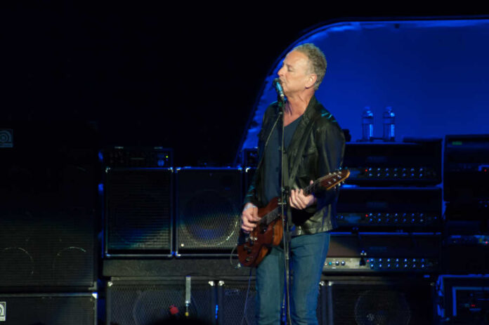 A guitarist performing on stage with amplifiers in the background