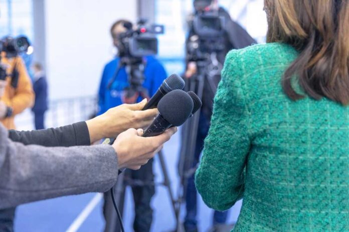 Hands holding microphones in front of a person at a press conference