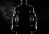 Silhouette of a muscular boxer holding gloves in a dark setting
