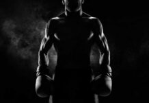 Silhouette of a muscular boxer holding gloves in a dark setting