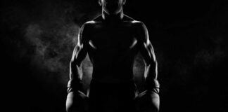 Silhouette of a muscular boxer holding gloves in a dark setting