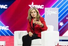 A woman in a red blazer speaking at a conference